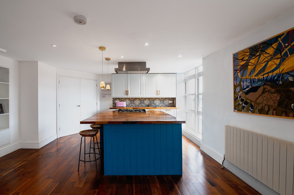 Modern kitchen in London featuring dark wooden flooring, a laminated wood island, and a custom tiled backsplash.