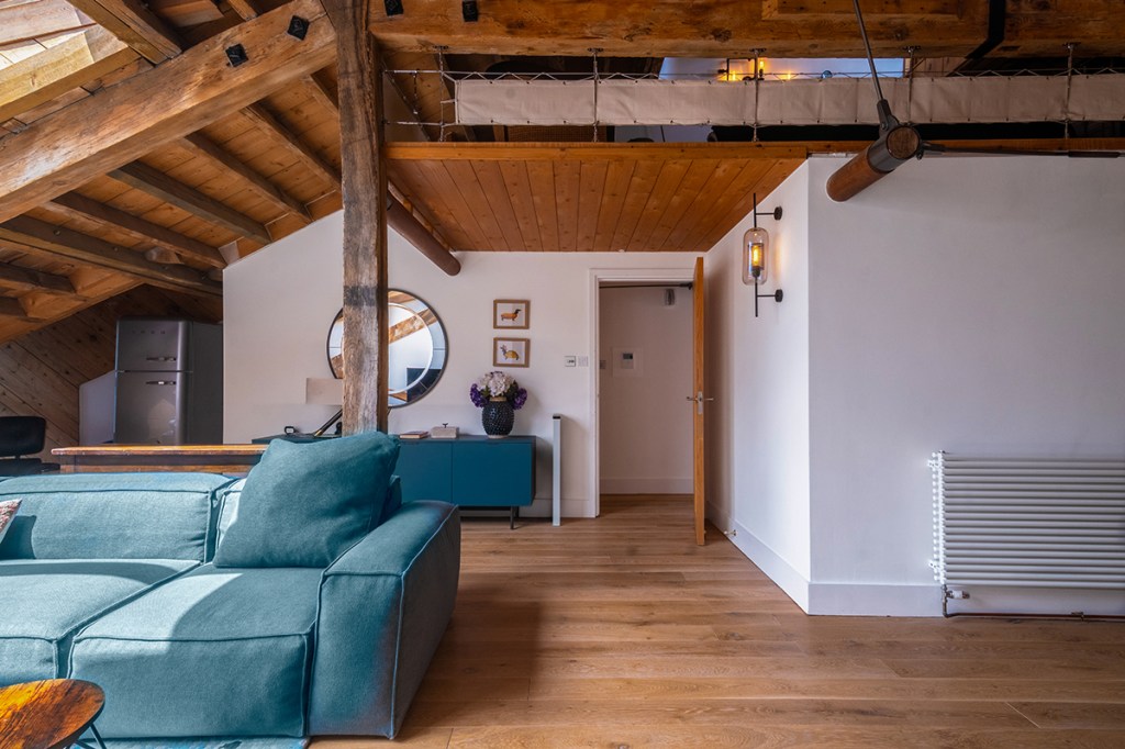 Interior of a top-floor converted apartment in London with exposed beams, skylights, open-plan living area, and modern contemporary design.