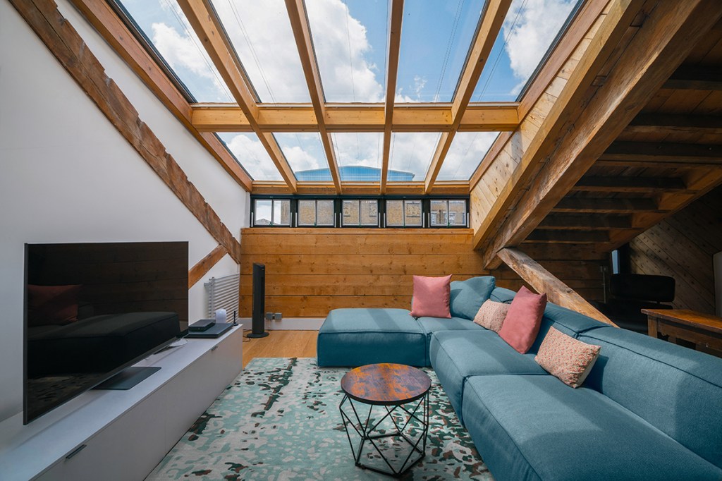 Interior of a top-floor converted apartment in London with exposed beams, skylights, open-plan living area, and modern contemporary design.